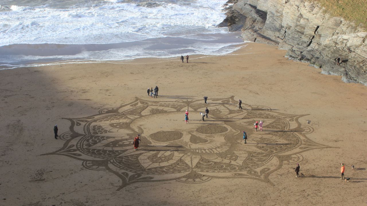 <strong>Ceding control: O</strong>ther beach-goers often help out the sand muralist. "I'm a bit of a perfectionist and it can be very easy to try and push people away, because they're not going to do it how you want it to be done," admits Treanor. <em>Pictured here: Skull art at Mwnt in south Ceredigion, Wales</em>