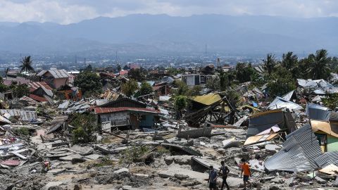 Residents walk amid debris in Palu on Tuesday.