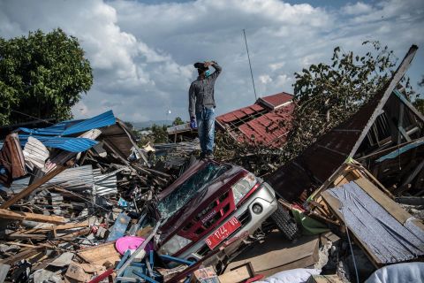 A man stands atop a car and other debris in Palu.