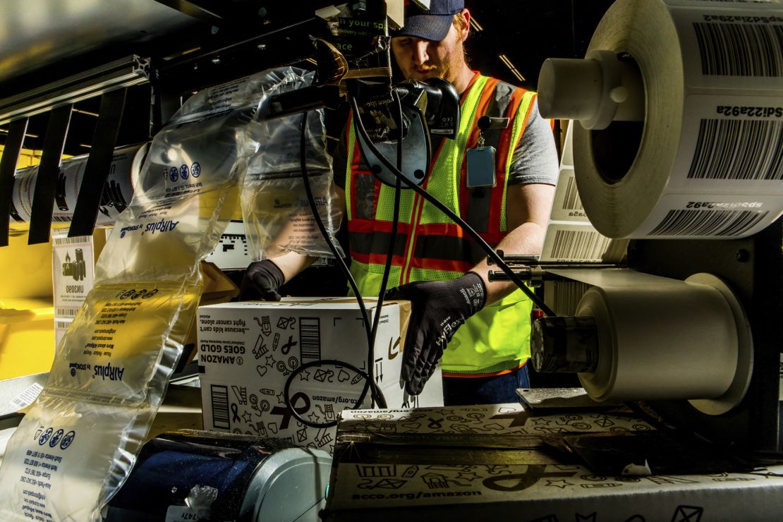 A fulfillment center employee builds and fills Amazon boxes with items before they ship out.