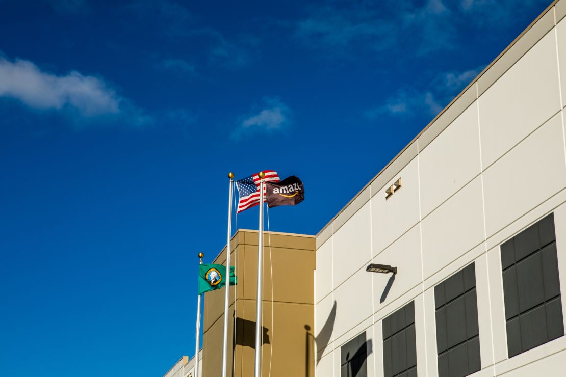 Flags for the United States, Washington state and Amazon wave in the wind outside the fulfillment center in Kent, Washington.