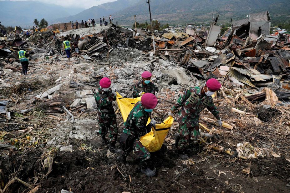 Soldiers carry a dead body from the ruins of houses in Palu, Indonesia, on Thursday, October 4.