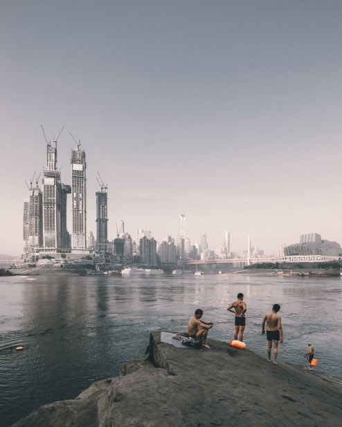 Chinese photographer Zhu Wenqiao captured swimmers on the riverside opposite the construction of Raffles City Chongqing, China designed by Safdie Architects.