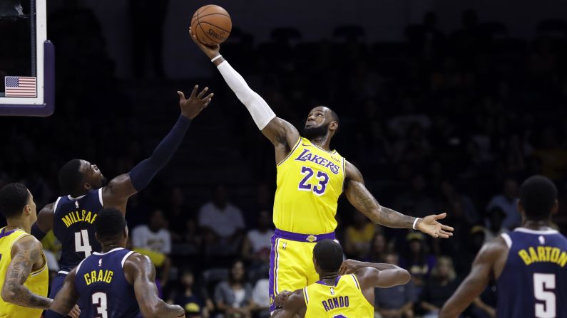 Los Angeles Lakers forward LeBron James grabs a rebound over Denver Nuggets forward Paul Millsap during the first half of an NBA preseason basketball game on Sunday, September 30, 2018.