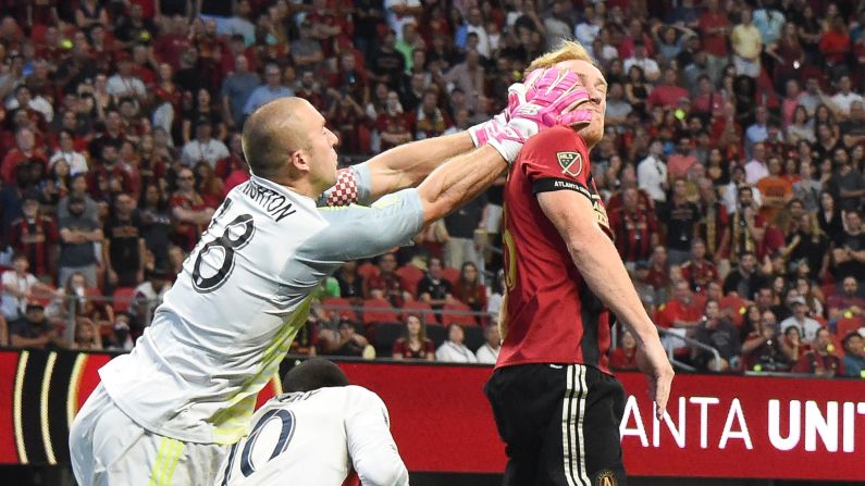 New England Revolution goalkeeper Brad Knighton grasps the face of Atlanta United defender Jeff Larentowicz during the first half of their match on October 6, 2018 at Mercedes-Benz Stadium in Atlanta, Georgia.