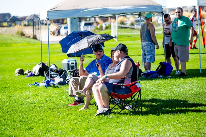 Fans shade themselves with umbrellas to guard against the 100 degrees Fahrenheit heat in Denver.