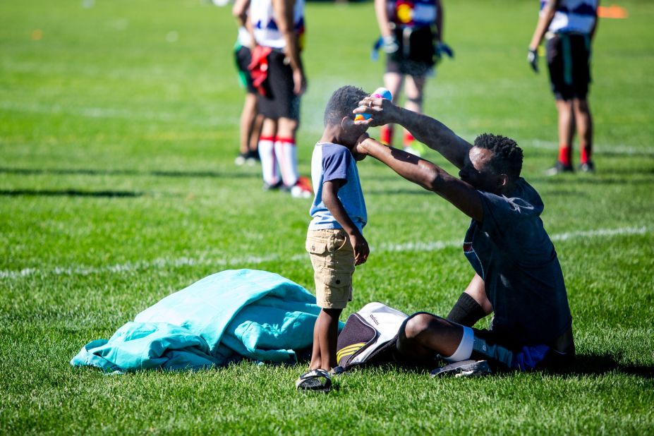 A player sprays his son with sunscreen to protect him from the scorching weather in Denver. 