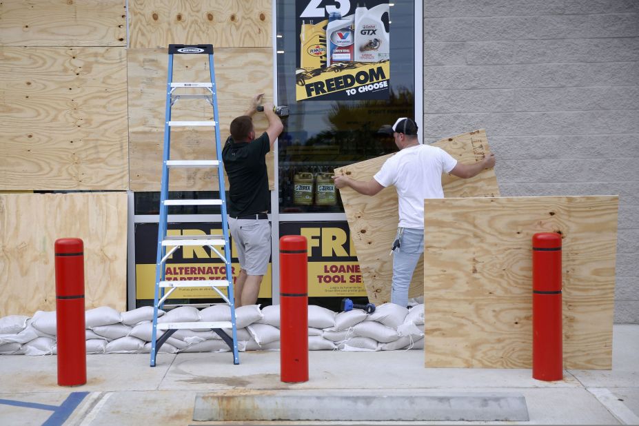 Justin Davis, left, and Brock Mclean board up a business in Destin, Florida, on Tuesday, October 9.