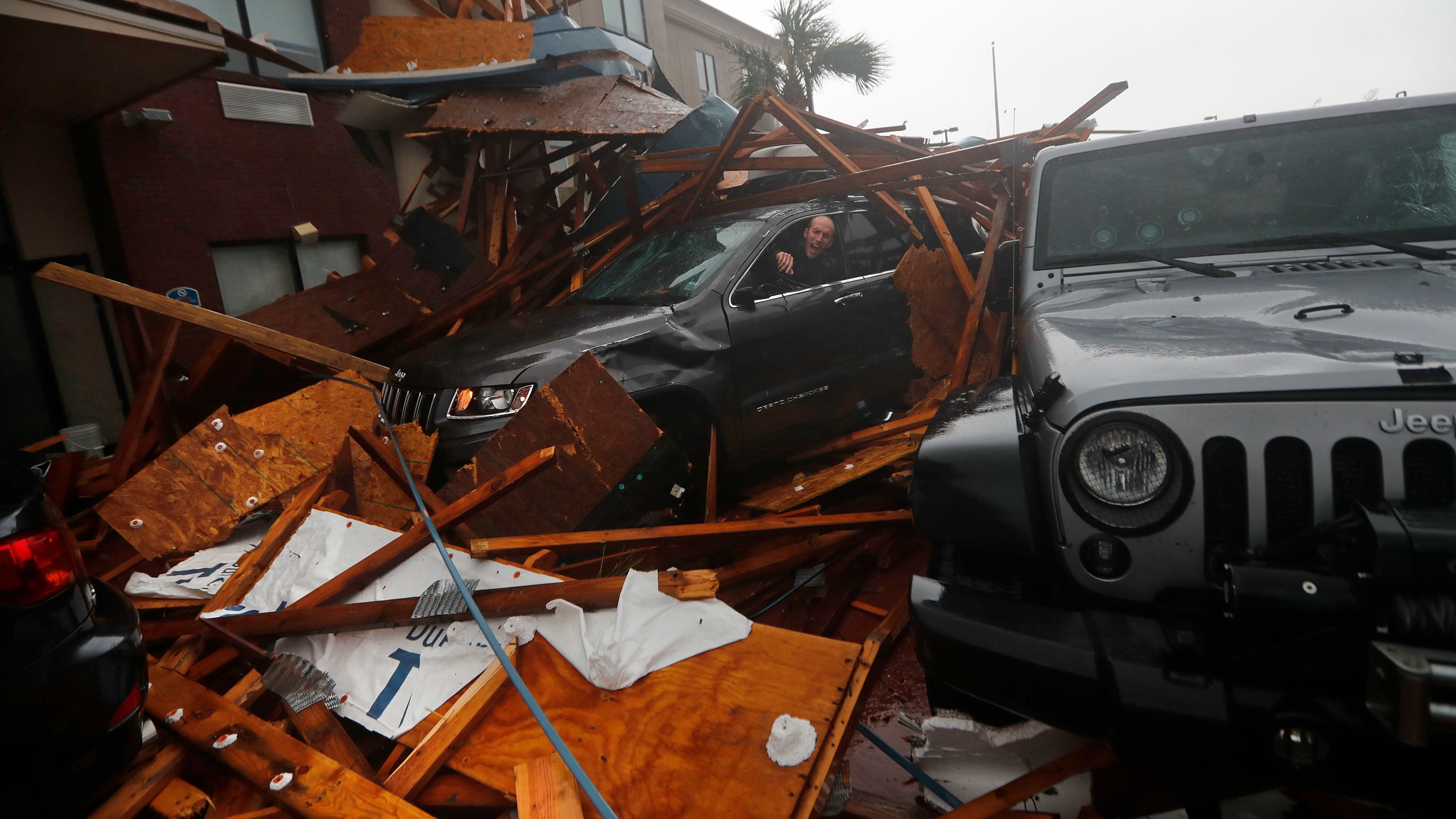 A storm chaser climbs into his vehicle to retrieve equipment after a hotel canopy collapsed in Panama City Beach on October 10.