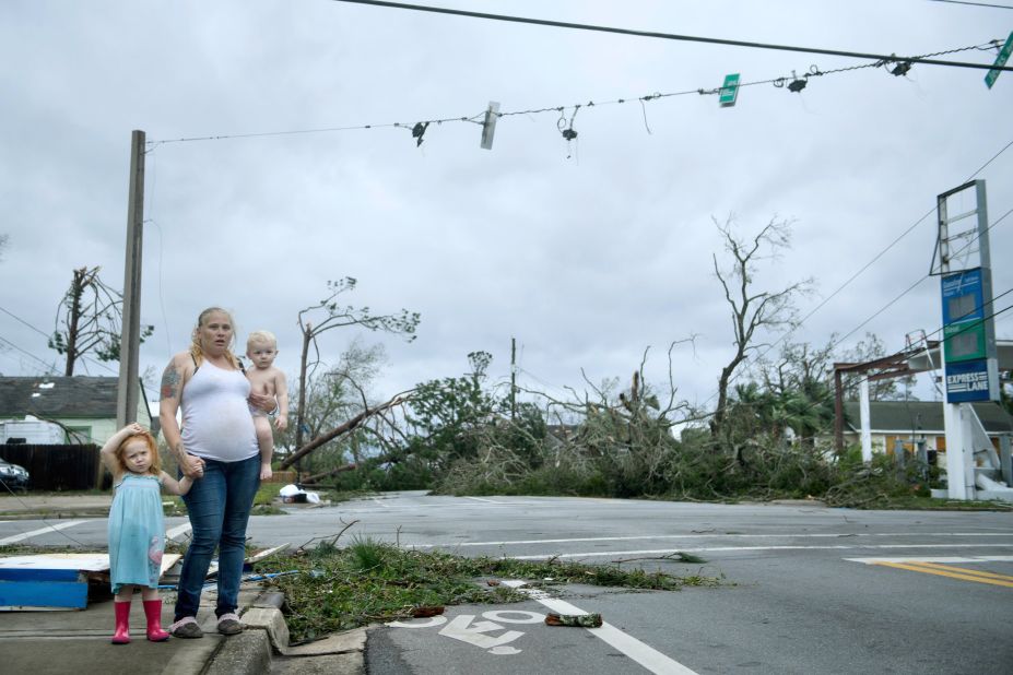 A woman and her children wait near a destroyed gas station in Panama City on October 10.