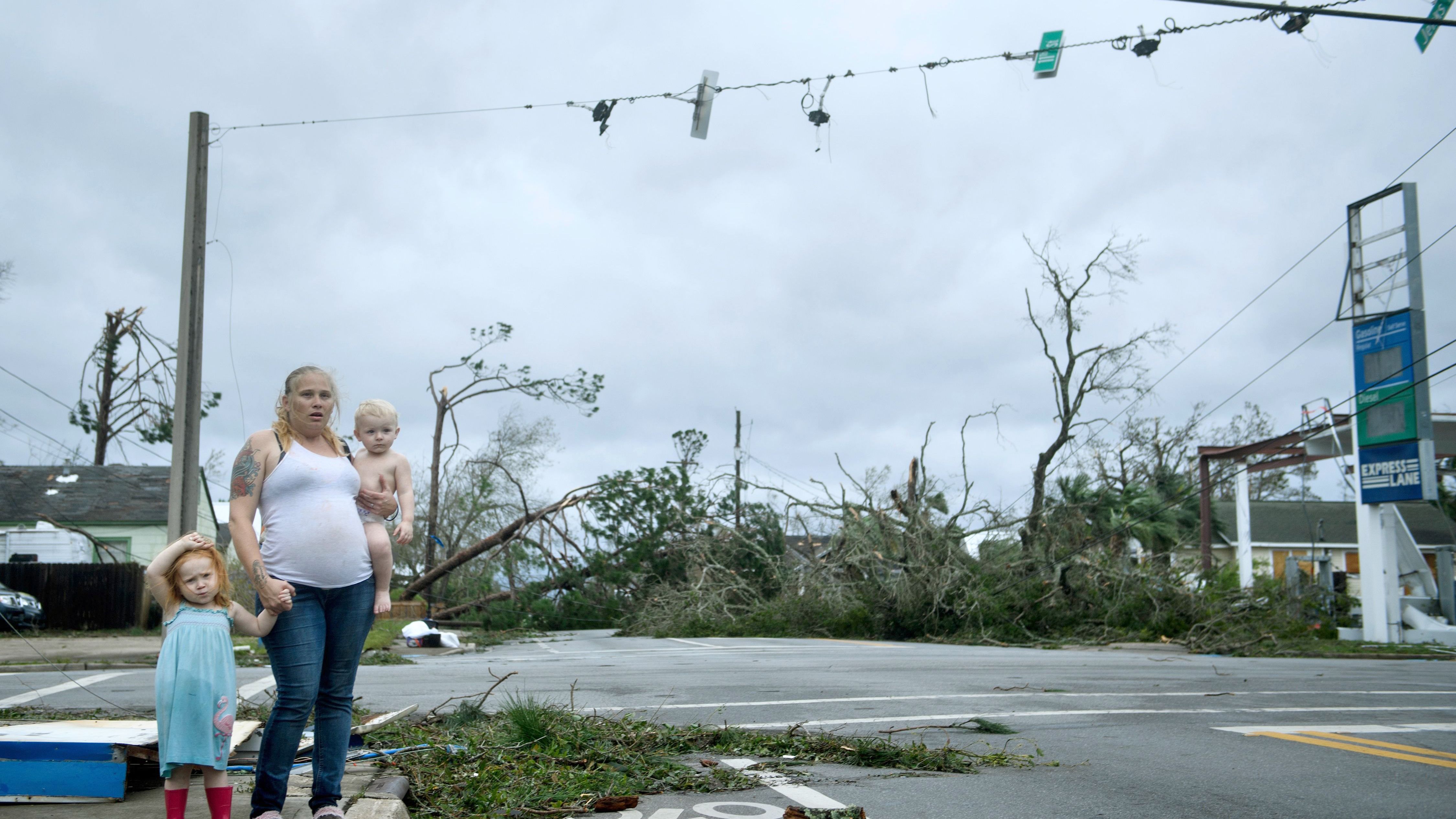 A woman and her children wait near a destroyed gas station in Panama City on October 10.