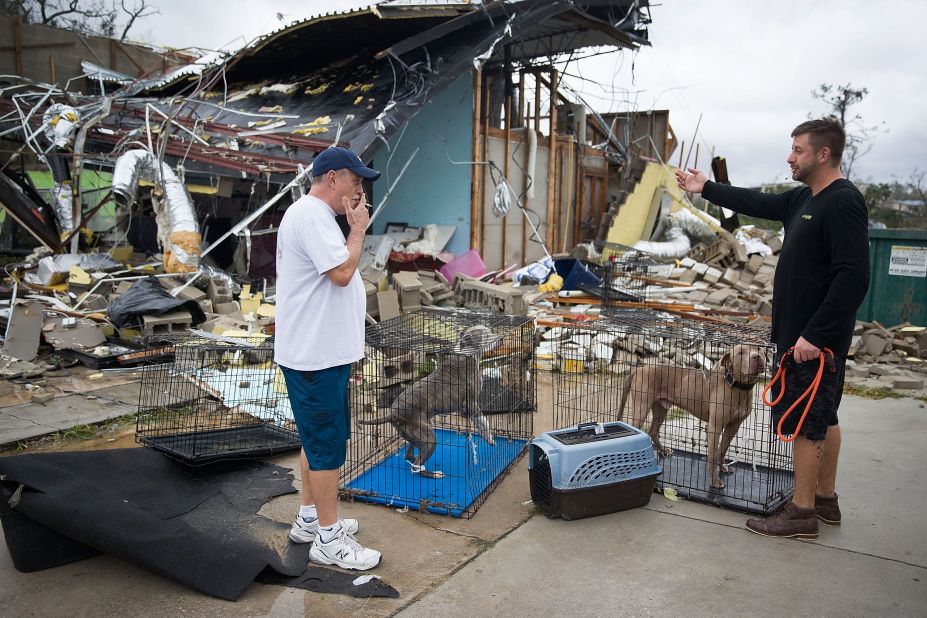 Rick Tesk, left, helps a business owner rescue his dogs from a damaged business in Panama City.