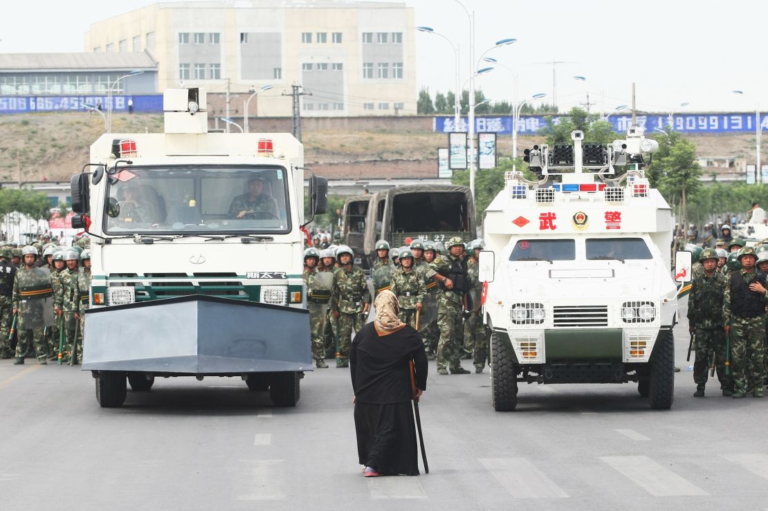 A woman stands in front of police and riot vehicles on July 7, 2009 in Urumqi, the capital of Xinjiang.