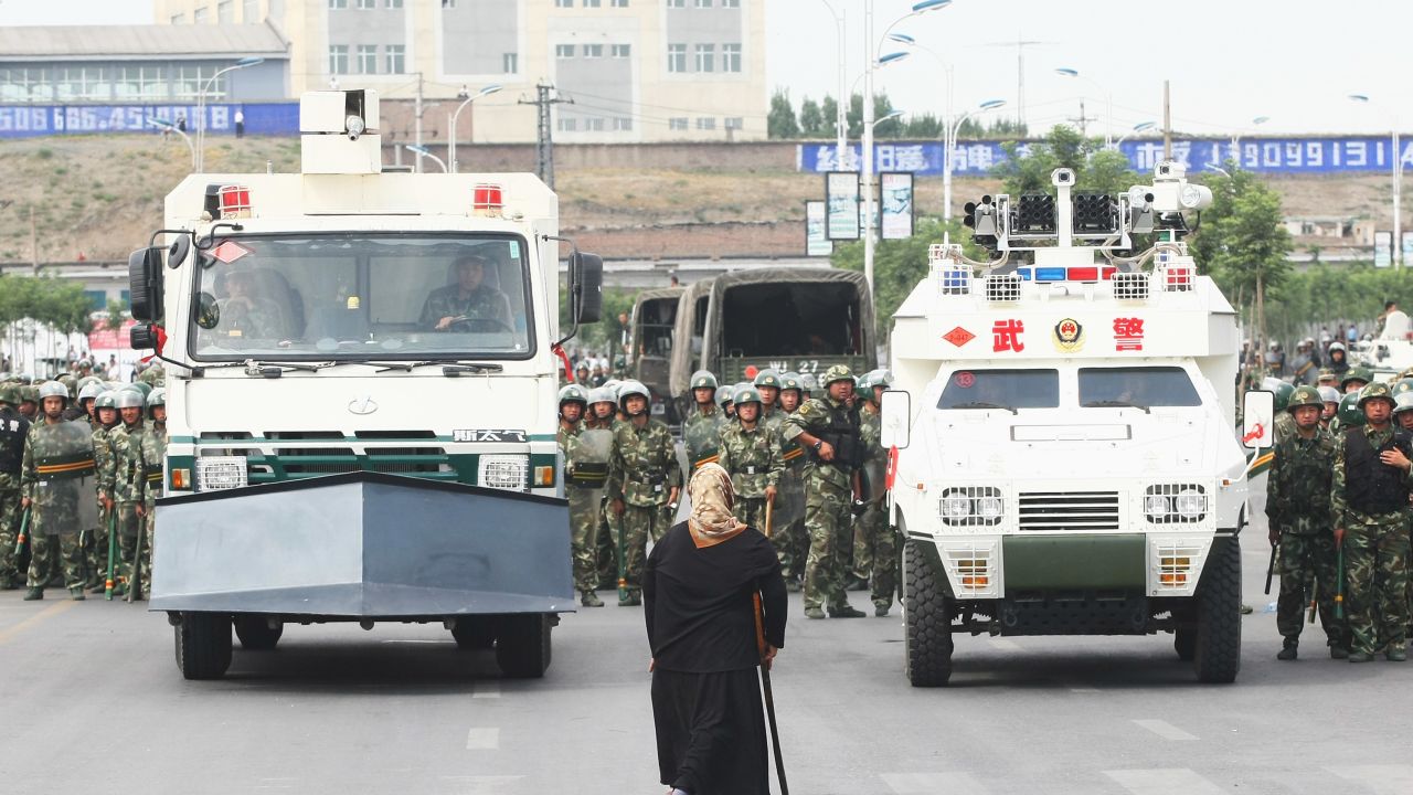 A woman stands in front of police and riot vehicles on July 7, 2009 in Urumqi, the capital of Xinjiang.