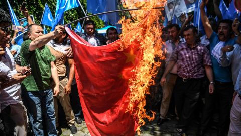 Protesters burn a Chinese flag during a demonstration to denounce China's treatment of Uyghurs in front of the Chinese consulate in Istanbul, on July 5, 2018.