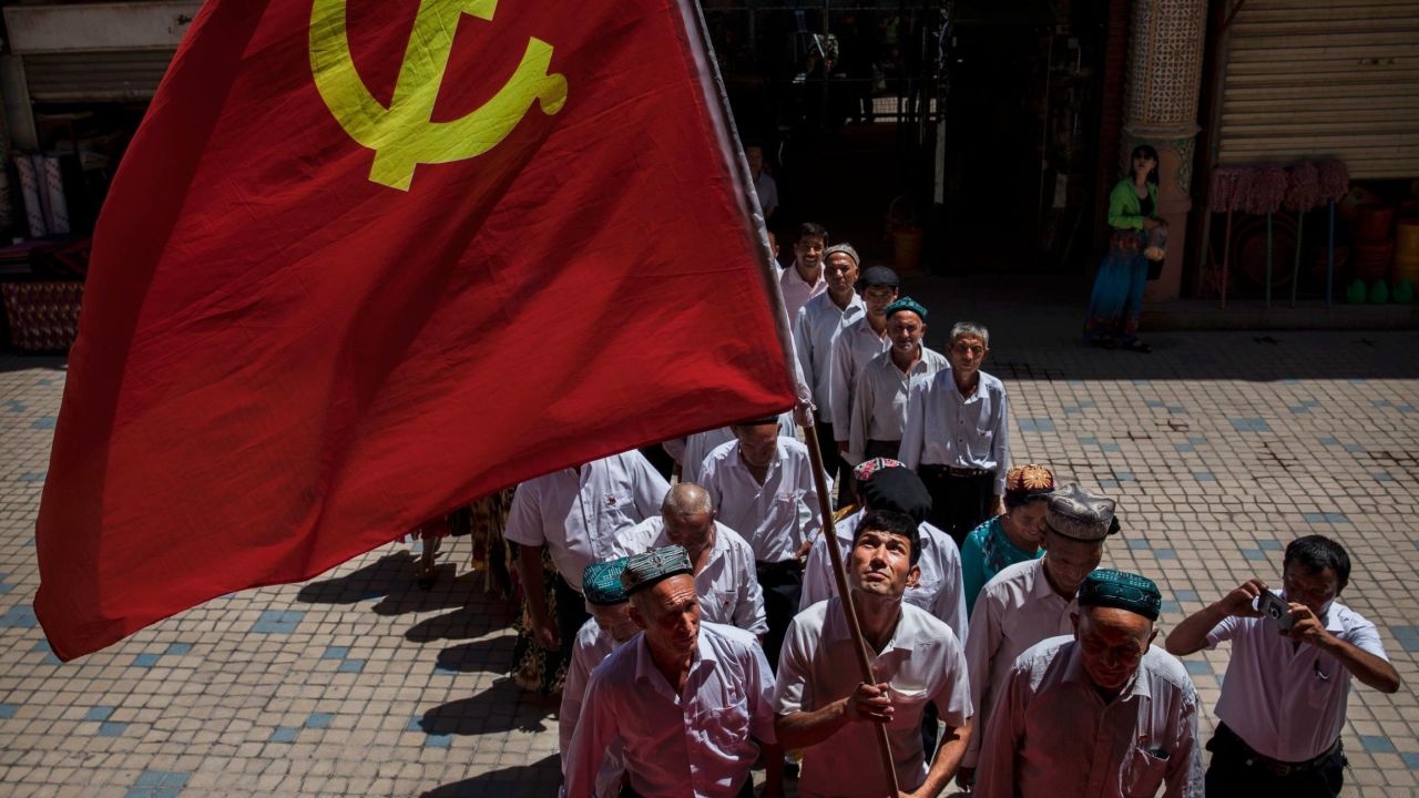 Ethnic Uyghur members of the Communist Party of China carry a flag as they take part in an organized tour on June 30, 2017 in the old town of Kashgar, in the far western Xinjiang province, China.