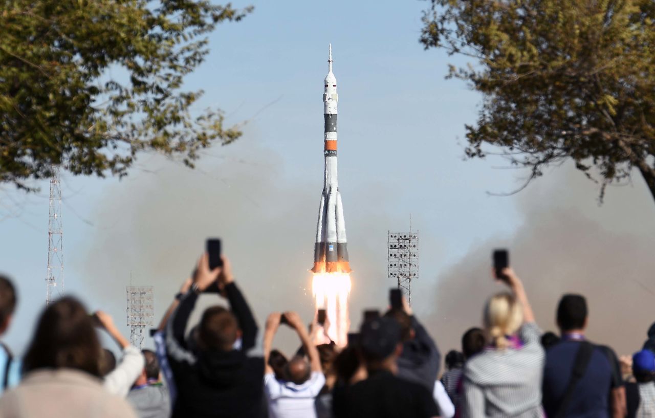 A crowd watches as the Soyuz-FG rocket booster lifts off from the Baikonur Cosmodrome. Dramatic footage minutes later showed the capsule carrying the crew as it parachuted back to Earth before thumping down in a plume of dust in Kazakhstan, about 250 miles away from where it took off.<br />