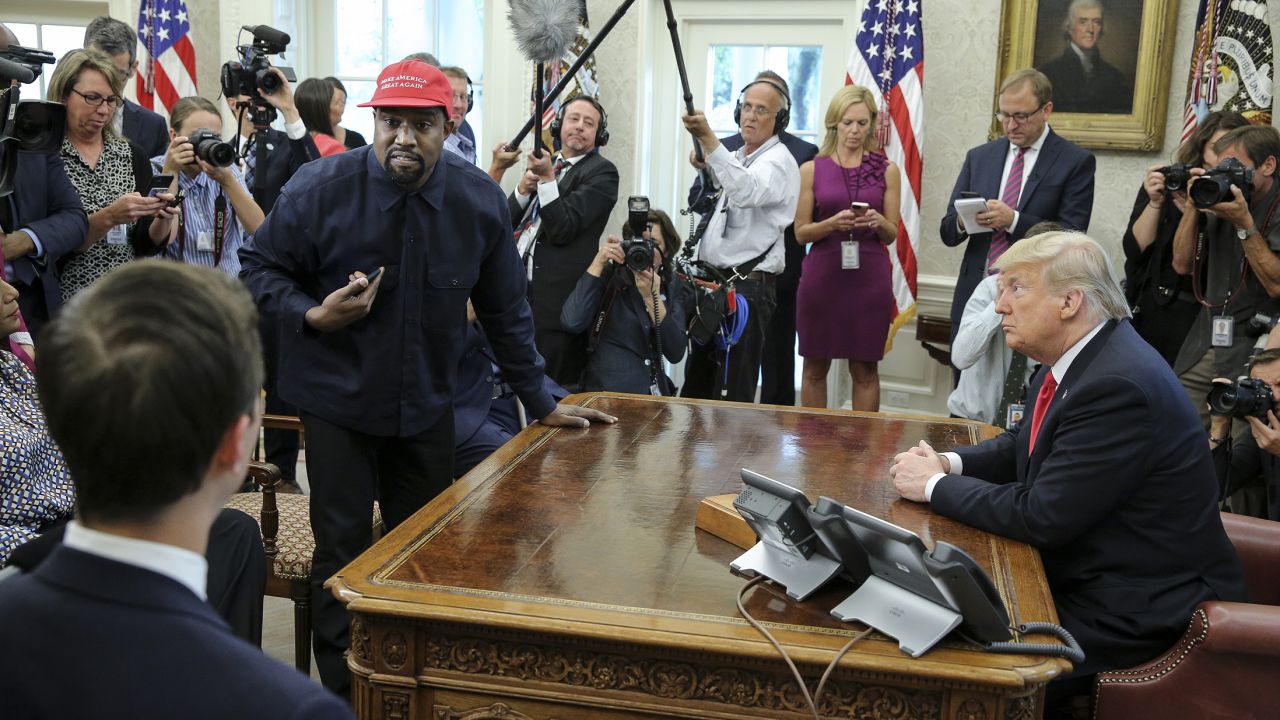Rapper Kanye West, second left, stands up as he speaks during a meeting with U.S. President Donald Trump in the Oval office of the White House on October 11, 2018 in Washington, DC.