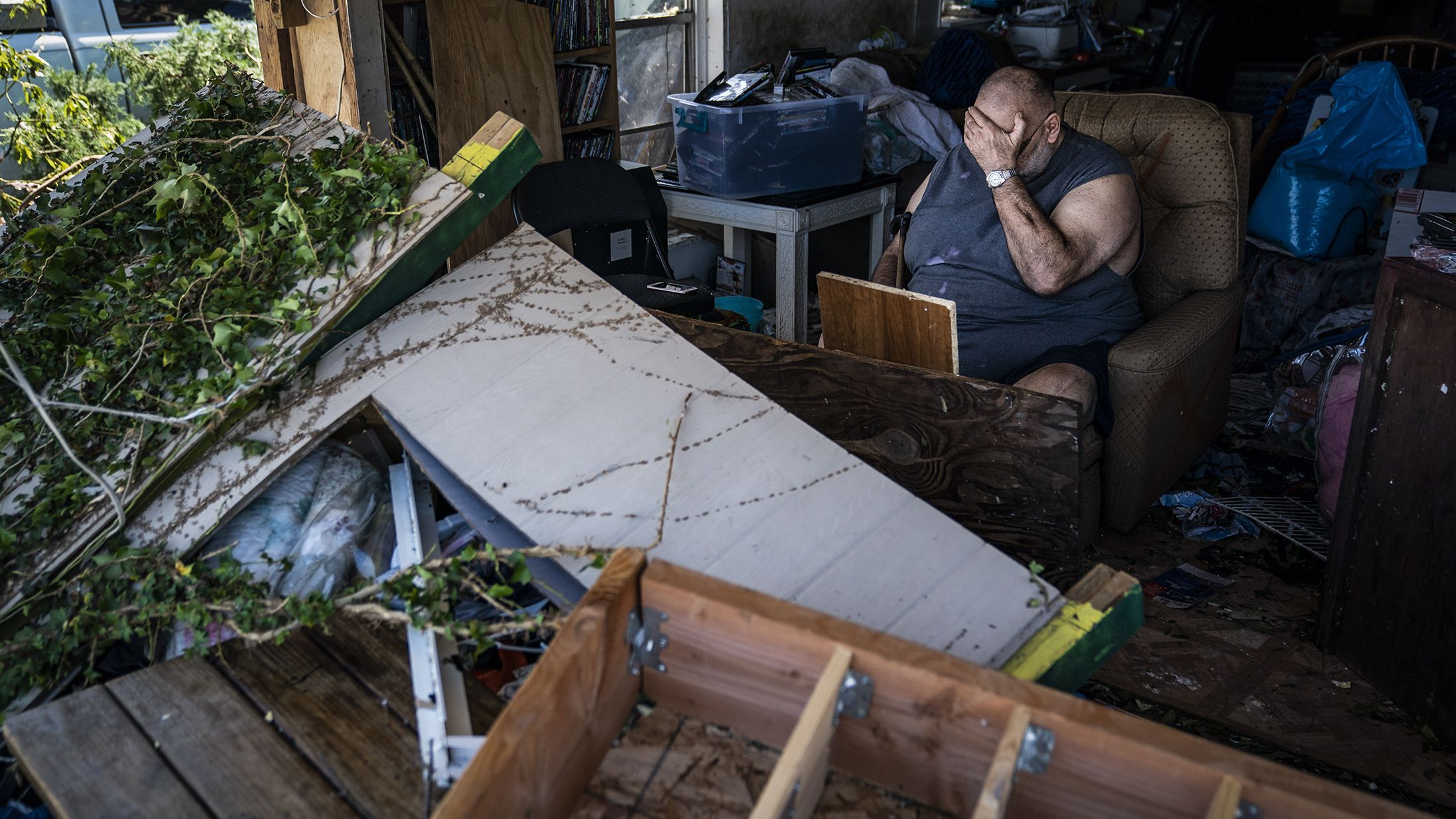 Benny Hobson sits in his recliner on Thursday, October 11, after losing the front wall of his house in Panama City, Florida.