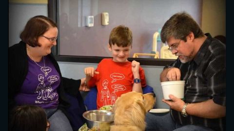 Thatcher Grayson sits with his parents, Jo and Donnie, and his service dog, Saul.