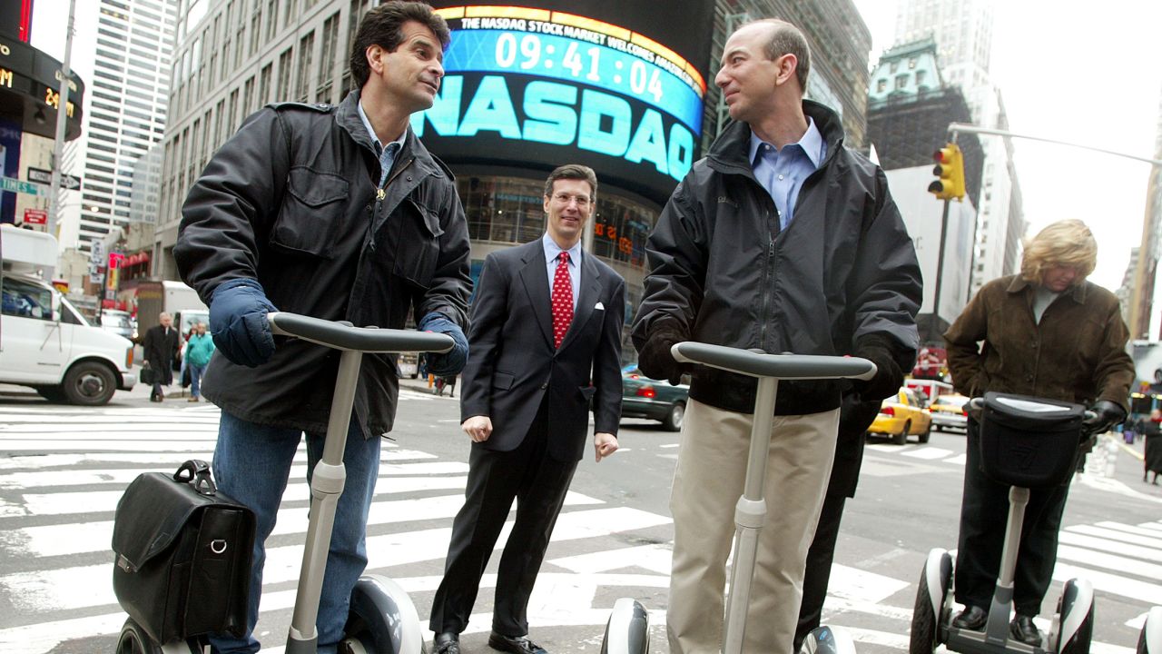 Amazon CEO Jeff Bezos stands on a Segway PT with Dean Kamen and NASDAQ Vice Chairman David Weild, center, after opening the NASDAQ on Nov. 18, 2002, the same day the device went on sale to the public. (Photo by Mario Tama/Getty Images) 