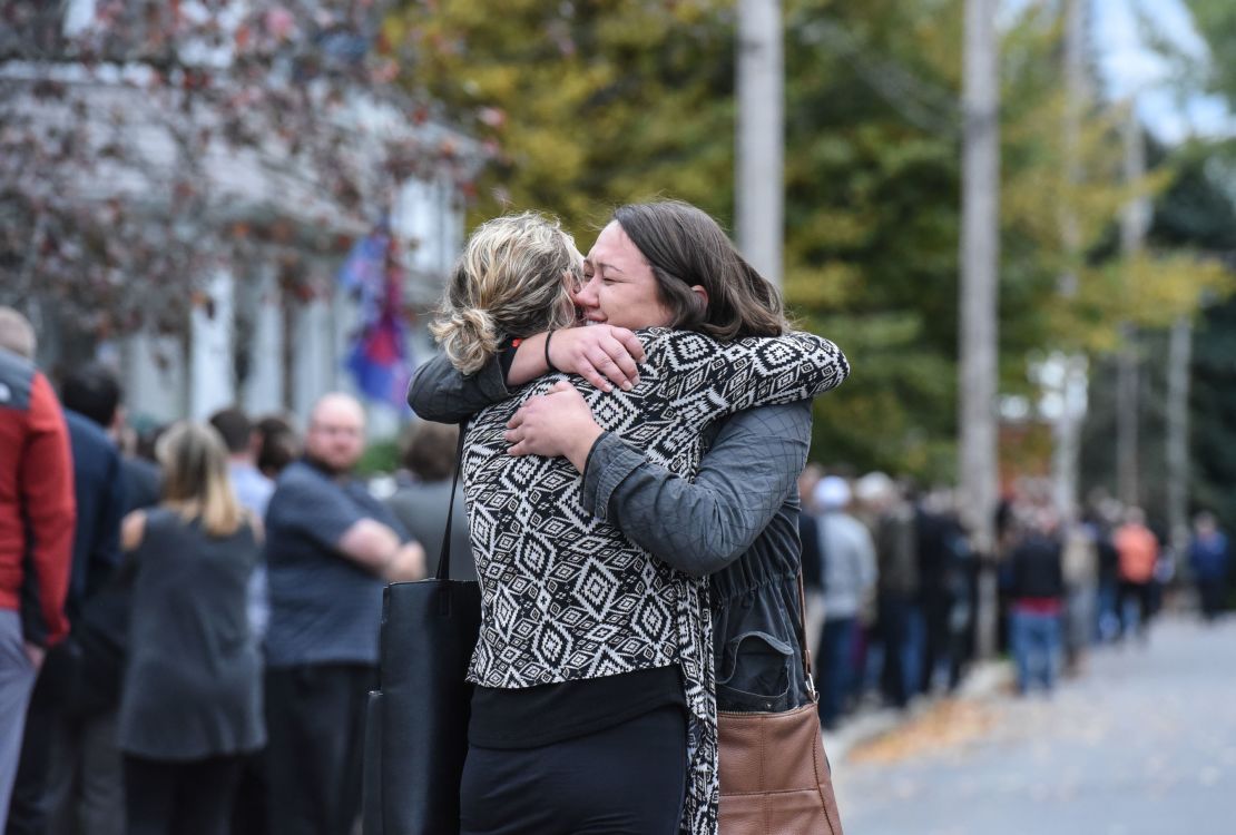 Two mourners embrace after leaving a service at St. Stanislaus Roman Catholic Church.