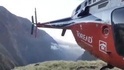 In this grab taken from video provided by SIMRIK AIR, a helicopter lands close to a storm site after searching for missing mountaineers on the Gurja Himal mountain, in Nepal, Saturday, Oct. 13, 2018. Seven people, including South Korean climbers, were killed and two more are missing on Gurja Himal mountain after a strong storm swept through their base camp, Nepalese police said Saturday. (SIMRIK AIR via AP)