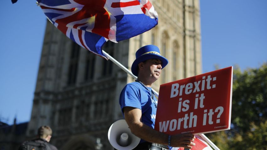 Anti-Brexit campaigner Steve Bray stands outside parliament with EU and Union Flags and a placard that reads "Brexit: is it worth it?" as he protests in Parliament Square in London on October 9, 2018. (Photo by Tolga AKMEN / AFP)        (Photo credit should read TOLGA AKMEN/AFP/Getty Images)