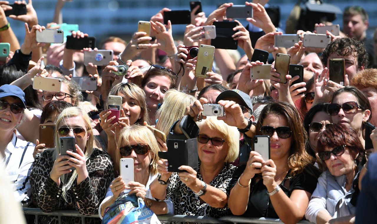 Well-wishers take photos of Harry and Meghan outside the Sydney Opera House.