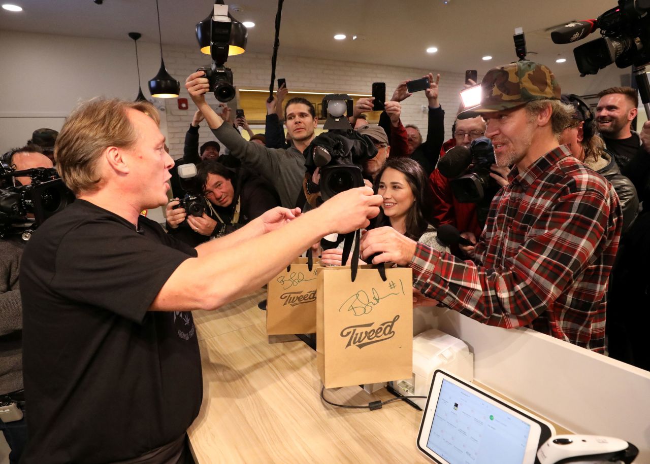 Canopy Growth CEO Bruce Linton hands bags to Ian Power, the first person in line to purchase recreational marijuana after midnight, at a Tweed retail store in St John's, Newfoundland.