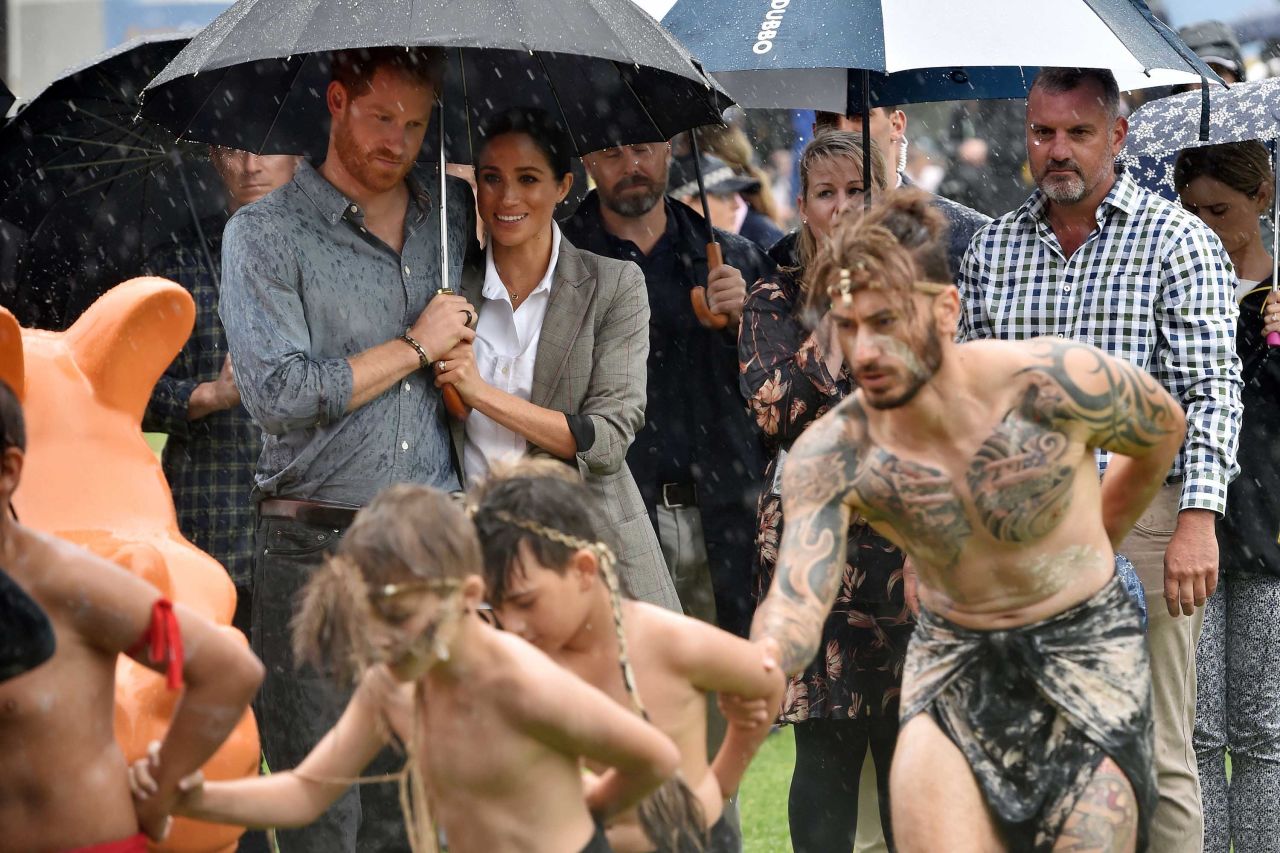 Harry and Meghan watch aboriginal dances from under an umbrella at Victoria Park in Dubbo.