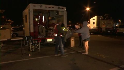 Relief workers deliver water and other supplies to a transit station parking lot that's serving as an evacuation point.