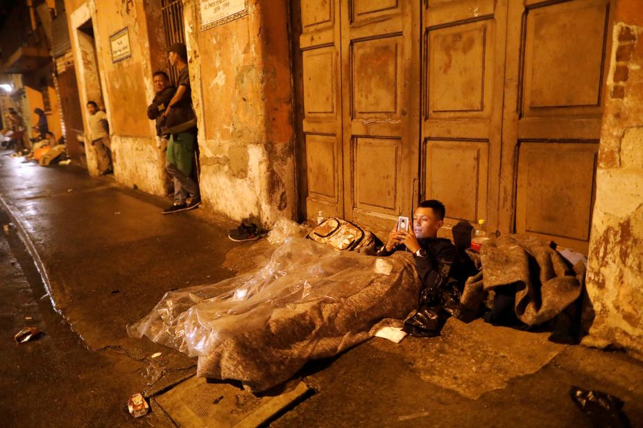 A Honduran migrant, part of the caravan, rests on a street as he looks through his mobile phone in Guatemala City on Wednesday.