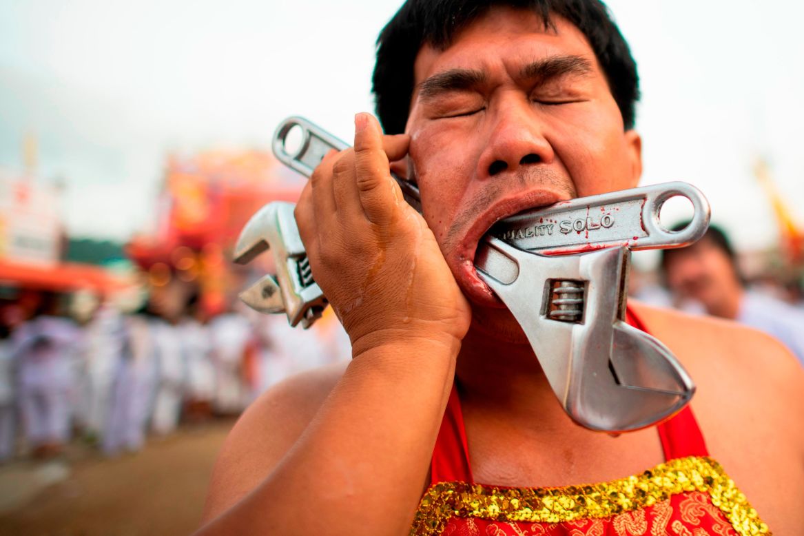 A Loem Hu Thai Su shrine devotee parades with two wrenches pierced through his cheek during the annual Vegetarian Festival in Phuket, Thailand, on Friday, October 12. Devotees pierce their cheeks with sharp objects and commit other painful acts to purify themselves and take on the sins of the community. 