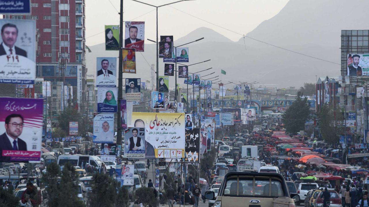 Kabul commuters drive past posters of candidates Monday during the legislative election campaign.