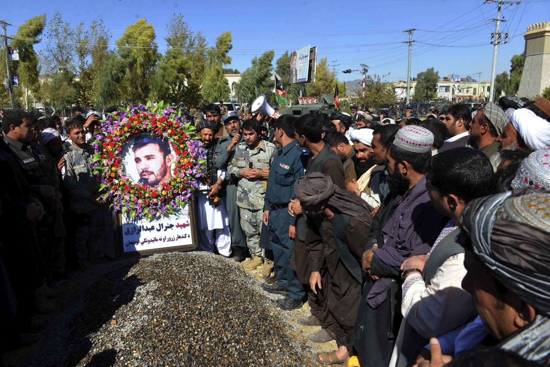 Civilians and military personnel stand beside the grave of Gen. Abdul Raziq, Kandahar police chief, during his burial in Kandahar on Friday.