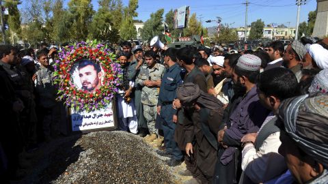 Civilians and military personnel stand beside the grave of Gen. Abdul Raziq, Kandahar police chief, during his burial in Kandahar on Friday.