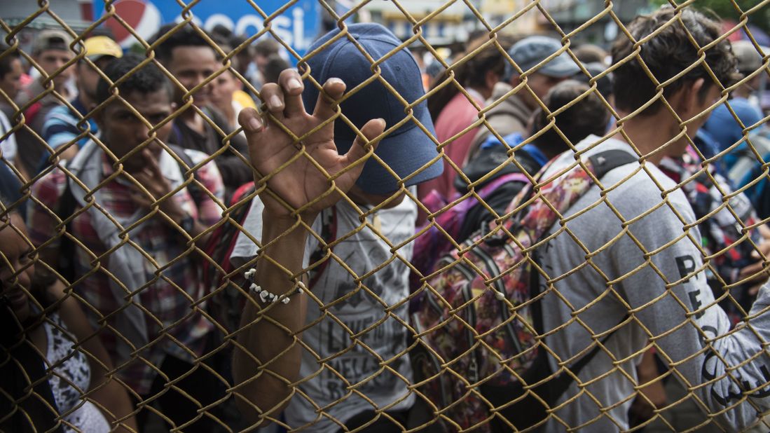 Honduran migrants wait at the Mexican border in Tecun Uman, Guatemala, on Friday, October 19. Thousands of migrants traveling in a caravan briefly moved toward the border crossing between the two countries before turning around. Guatemala has closed its border gate and is standing guard with dozens of troops and two armored jeeps. 