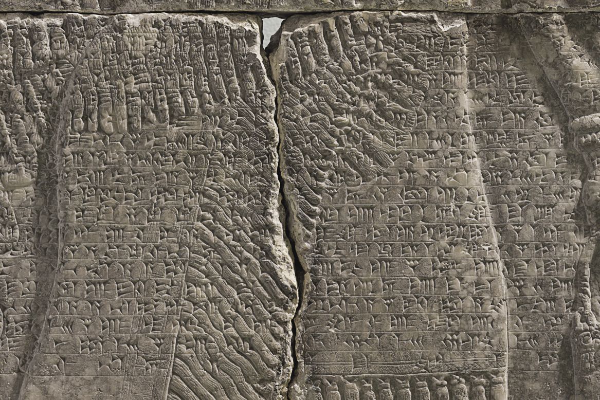 A band of text written in cuneiform -- one of the earliest systems of writing -- runs across the center of the panel. 