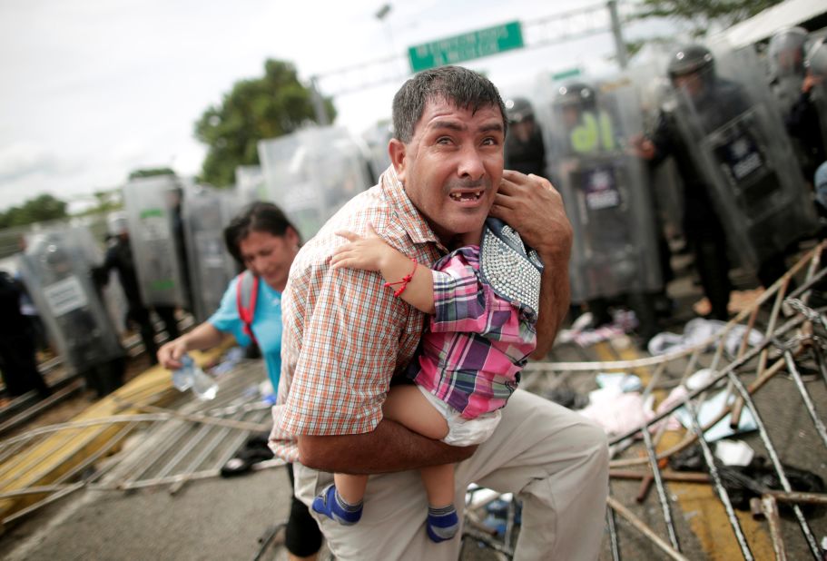 A Honduran man protects his child after fellow migrants, part of a caravan trying to reach the United States, stormed a border checkpoint in Guatemala, in Ciudad Hidalgo, Mexico, Friday, October 19.
