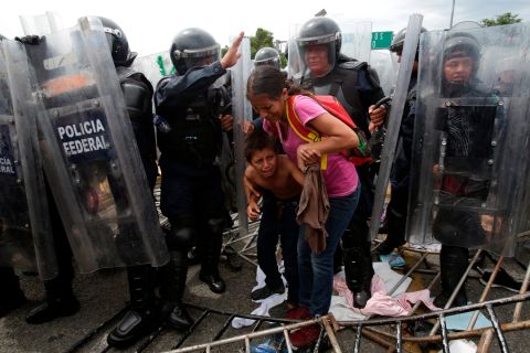 A Honduran migrant mother and child are surrounded by Mexican Federal Police in riot gear, at the border crossing in Ciudad Hidalgo, Mexico, Friday, October 19. 