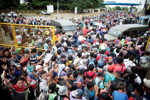 Honduran migrants, part of a caravan trying to reach the United States, storm a border checkpoint to cross into Mexico, in Tecun Uman, Guatemala, Friday, October 19. 