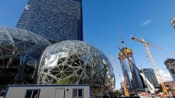 In this Wednesday, Oct. 11, 2017, photo, large spheres take shape in front of an existing Amazon building, behind, as new construction continues across the street in Seattle. Memo to the many places vying for Amazon's second headquarters: It ain't all food trucks and free bananas. For years now, much of downtown Seattle has been a maze of broken streets and caution-taped sidewalks, with dozens of enormous cranes towering overhead as construction trucks rumble past pedestrians and bicyclists. And while Amazon is far from solely to blame for these issues, and many say the benefits clearly outweigh the drawbacks, life has been disrupted. 