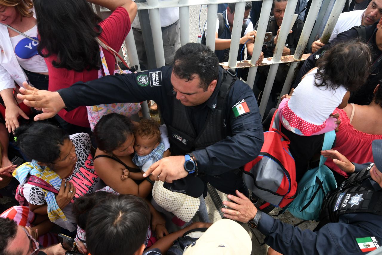 Mexican federal police officers allow women and children taking part in a caravan of Honduran migrants heading to the United States to cross to Mexico in the border city of Tecun Uman, Guatemala, on Friday, October 19. 
