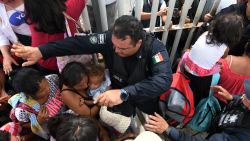 Mexican federal police officers allow women and children, taking part in a caravan of Honduran migrants heading to the US, to cross to Mexico in the border city of Tecun Uman, 257 kilometers south of Guatemala City, on October 19, 2018. - Honduran migrants who have made their way through Central America were gathering at Guatemala's northern border with Mexico on Friday, despite President Donald Trump's threat to deploy the military to stop them entering the United States. 