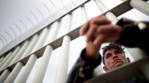 A Honduran migrant looks out from a gate on a bridge connecting Mexico and Guatemala in Tecun Uman, Guatemala.