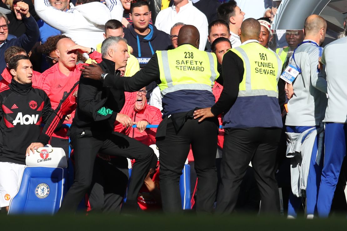 Stewards hold back Jose Mourinho as he clashes with the Chelsea backroom staff during Saturday's Premier League match.