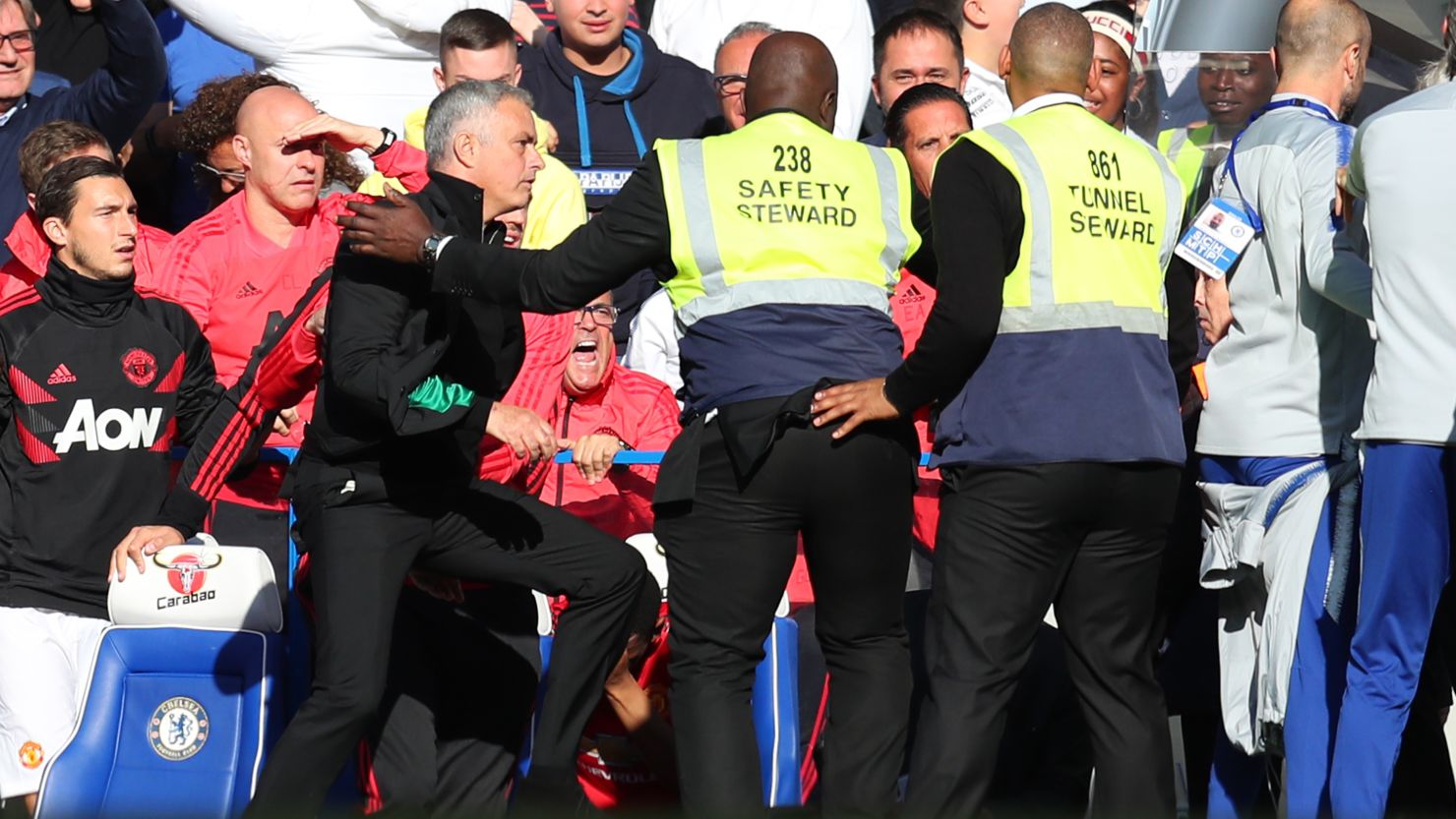 Stewards hold back Jose Mourinho as he clashes with the Chelsea backroom staff.