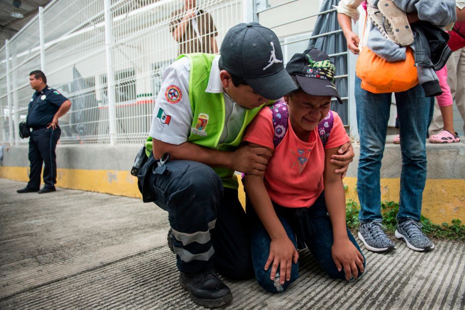 A migrant is comforted by a Mexican paramedic after her mother fainted while crossing the border between Guatemala and Mexico.