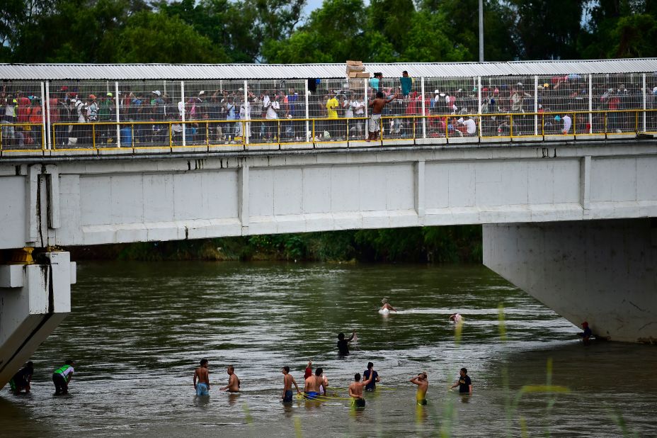 Honduran migrants help some of their members get down to the Suchiate River from the Guatemala-Mexico border bridge in Ciudad Hidalgo on Saturday.